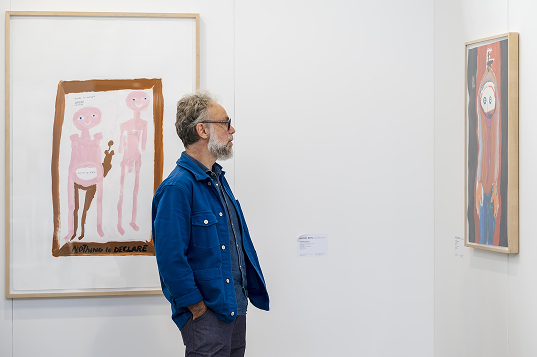 Visitor viewing framed artworks at Art on Paper